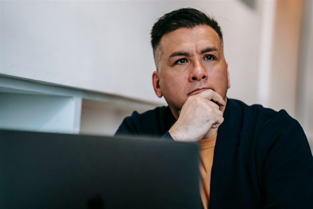 A professional thinking calmly at a laptop, working out their next step